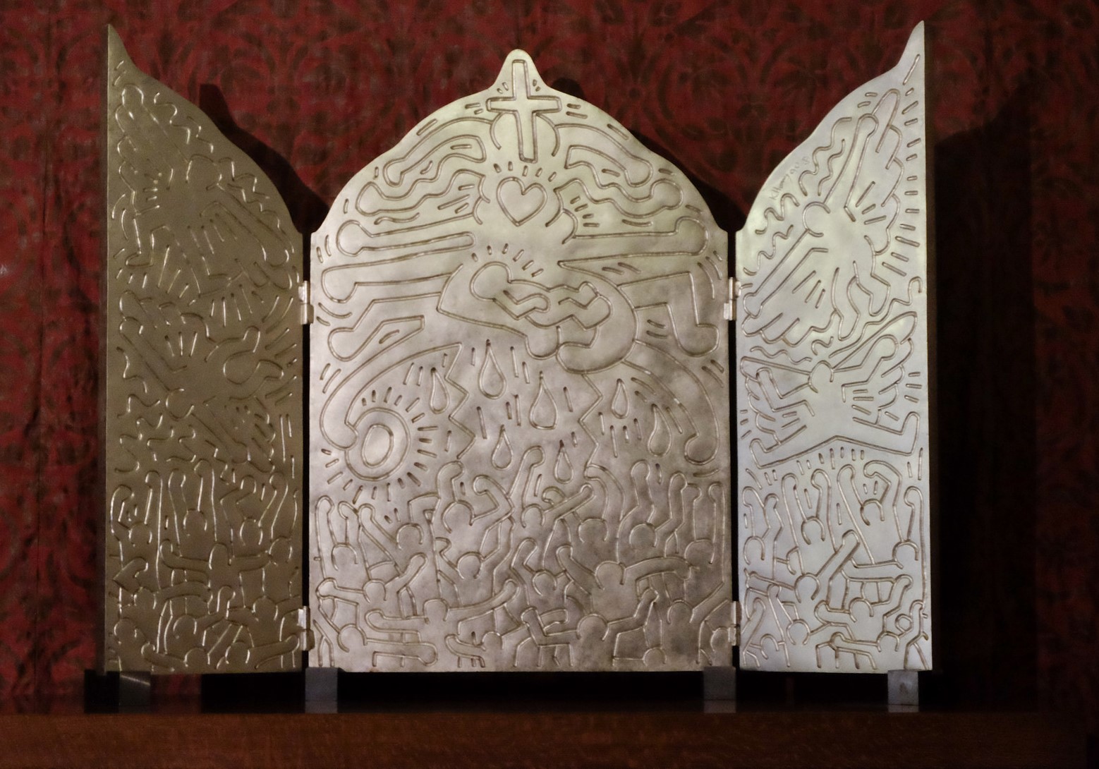 Op 'The Life of Christ' van Keith Haring (1958-1990) schenkt de Vader, gesymboliseerd door het hart boven het kind, met brede gebaren 'The Radiant Child', zijn stralende kind, aan de mensen. Zijn zachtheid deint uit naar de menigte met gebalde vuisten. © Flickr Op 'The Life of Christ' van Keith Haring (1958-1990) schenkt de Vader, gesymboliseerd door het hart boven het kind, met brede gebaren 'The Radiant Child', zijn stralende kind, aan de mensen. Zijn zachtheid deint uit naar de menigte met gebalde vuisten. © Flickr
