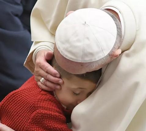 Paus Franciscus knuffelt een kind tijdens de algemene audiëntie © SIR
