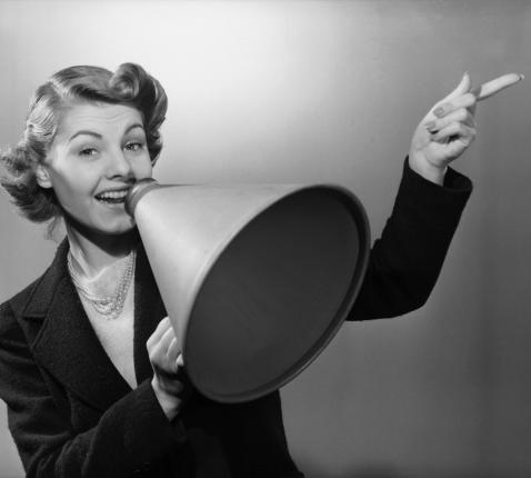 Original Caption: Portrait of a woman holding a megaphone and pointing to her left. Undated photograph. © Tullio Saba (flickr.com/people/97453745@N02/)