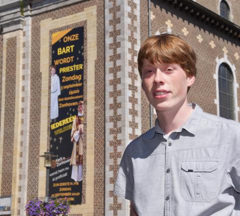 Je kan er niet naast kijken: aan de kerk hangt een groot spandoek met 'Onze Bart wordt priester'. © Tony Dupont
