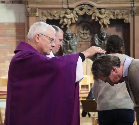 Mgr. Hoogmartens strooit assen op het hoofd van bisschoppelijk geledegeerde Frank Deloffer op Aswoensdag © Jente Vandewijer