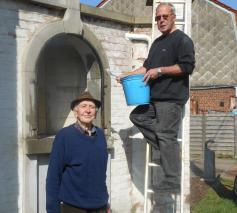 Maurice Debremaeker met de schuurborstel nog in de handen bij de renovatie van zijn laatste kapel, met name die van Maurice Winderickx. Rechts op de ladder Zéphirin (Zef) Swaelens, intussen zijn waardige opvolger. Foto eind maart 2019. © jh