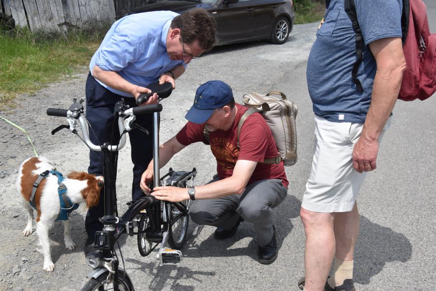 Een wandelaar verhelpt een mechanisch probleem aan de bisschoppelijke fiets. © PDL