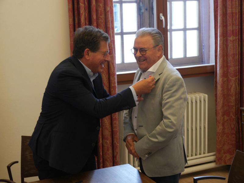 Secretaris Willy De Four krijgt het ereteken opgespeld. © Brugge-Mariastad vzw