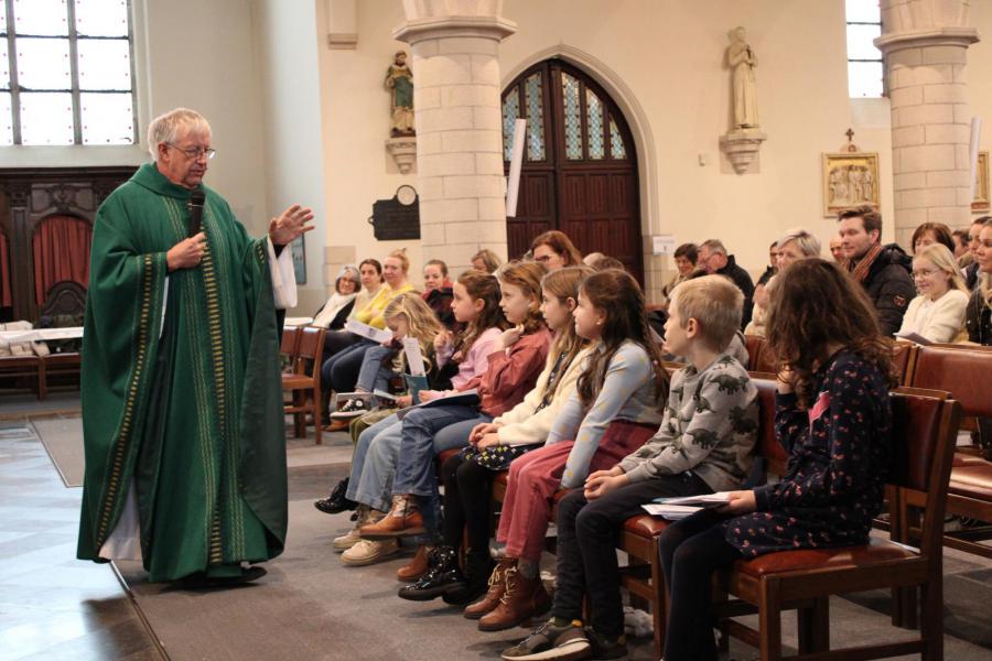 Priester Jan spreekt de eerste communicanten toe 