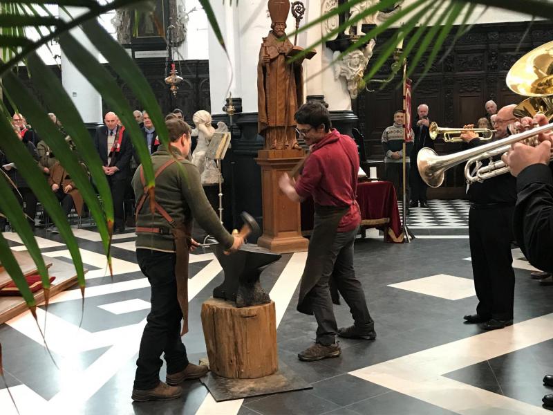 Bruno Kristo en Olivier Sarrazyn hameren op het aambeeld met het beeld van Sint-Elooi op de achtergrond  © Benoit Lannoo