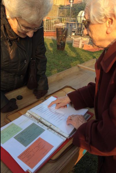Twee oud-leidsters tonen de oudste documenten aan de huidige leiding.