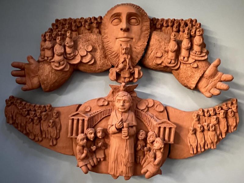 Terracotta hoogreliëf met een voorstelling van paus Pius X die de jonge kinderen uitnodigt tot de heilige communie, werk van May Claerhout uit 1980 © Dirk Bellens