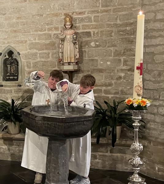 De misdienaars gieten het water in de doopvont 