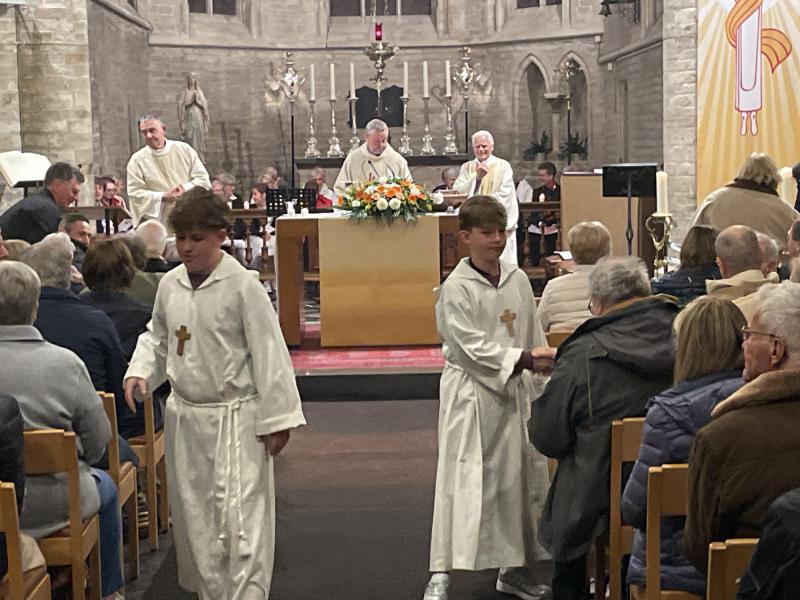 De misdienaars geven de vredeswens door in de kerk 