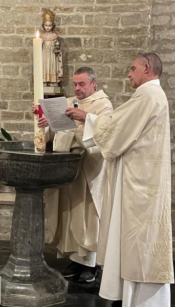 Diaken Johan dompelt de paaskaars in het water van de doopvont en pater Patrick spreekt het wijdingsgebed uit. 