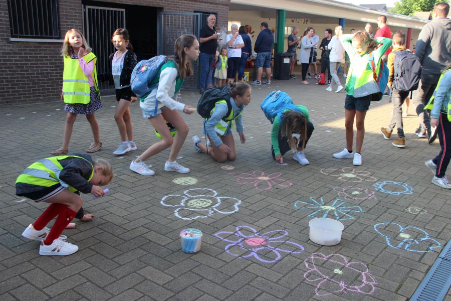 Tijdens het onthaal mogen de kinderen met stoepkrijt een bloementapijt op de speelplaats tekenen. 