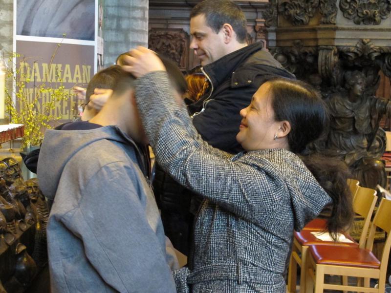 De ouders leggen het kruisje op aan hun kind: een bijzonder moment. © Leen 