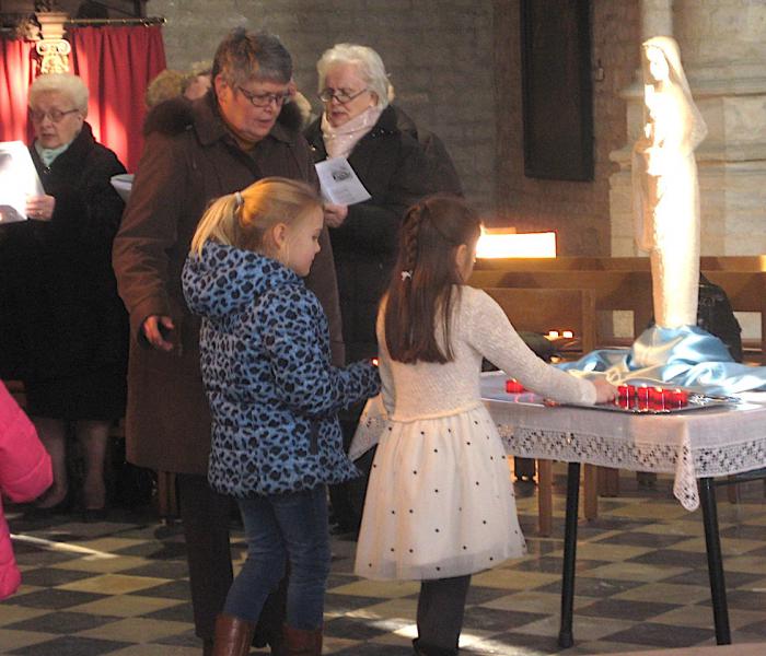 Eerstecommunicantjes branden een kaarsje bij het Mariabeeld. © L. J. 