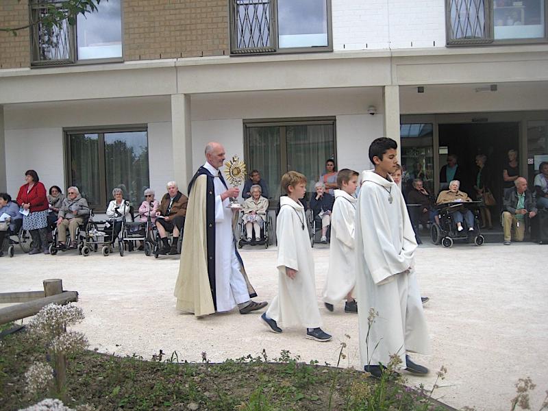 De bewoners van het Parkhof zaten goed geschermd onder de galerij. Na de zegen maakte deken Piet Capoen tijd om met het Heilig Sacrament tot bij hen te gaan. © Lydia Van Buggenhout 