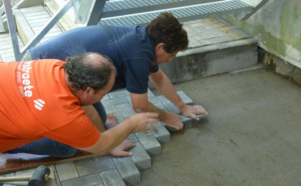 Bisschop Lode hielp mee bij het leggen van klinkers onder de nieuwe noodtrap. © Filip Bonduel