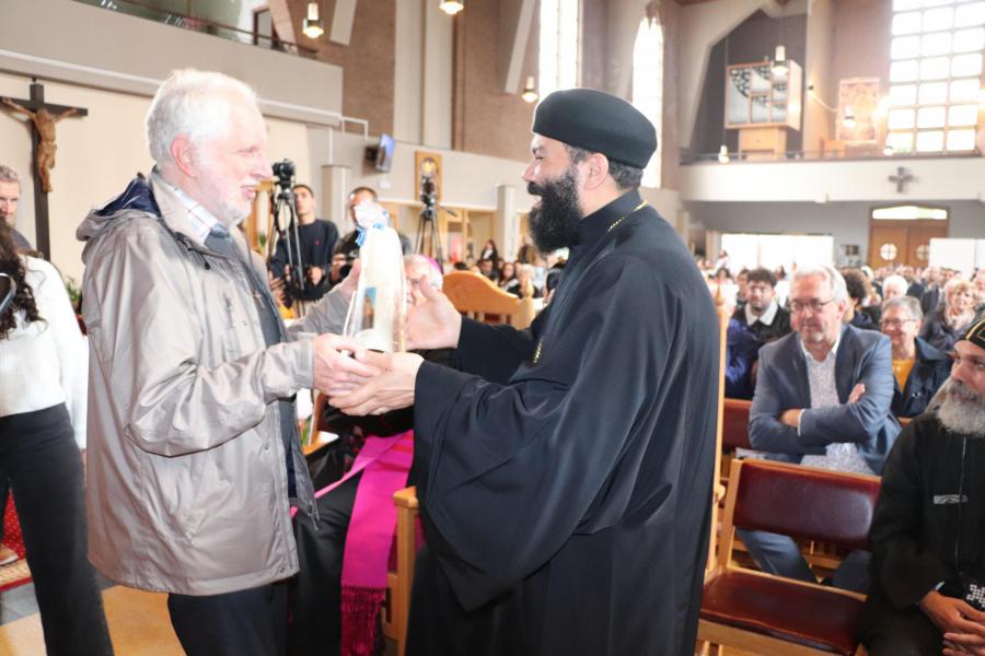 Vader Moussa, pastoor van de Koptisch Orthodoxe gemeenschap, ontvangt als aandenken aan deze dag een kaars 