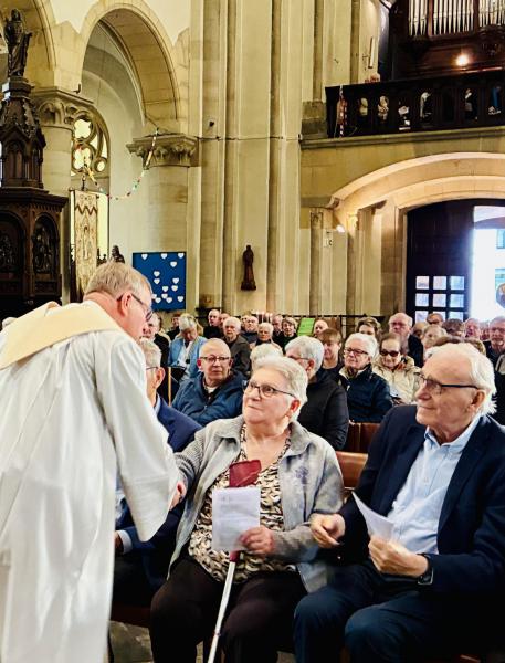 Pastoor Jan schudt hand en wenst vrede toe aan parochianen 