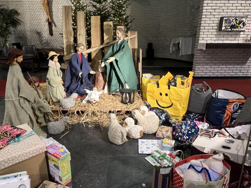 De kerststal met de geschenken die de kinderen tijdens de gezinsviering meebrachten voor kinderen die het minder goed hebben. © Dirk Bellens