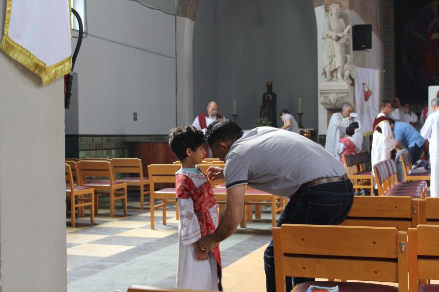 De papa helpt de misdienaar bij het aankleden © JvR