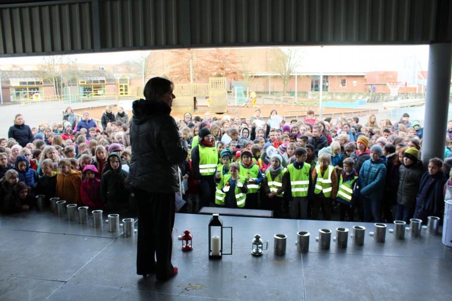 De burgemeester spreekt de kinderen van de Gemeentelijke Basisschool toe. Voor elke klas staat een kandelaar klaar. © Guido Dumon