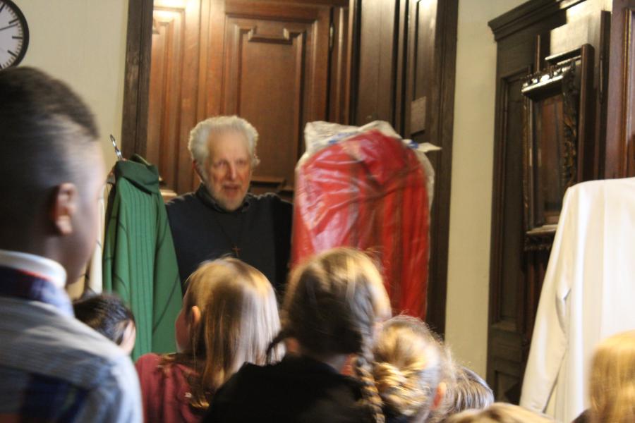 Priester Jos toont de verschillende kleuren van de gewaden 