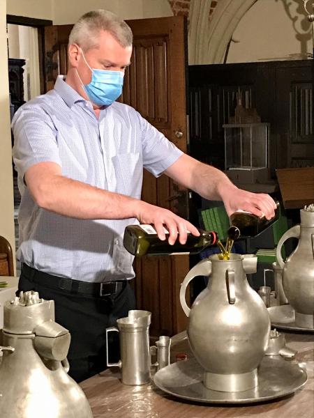 Voorbereiding chrismaviering 2021 - koster Johan vult de kruiken met olijfolie 