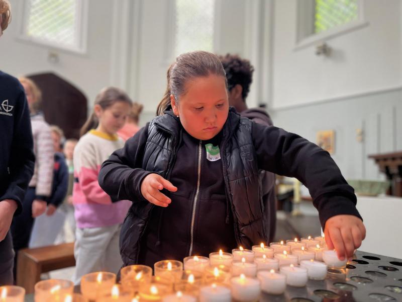 Kinderen denken aan iemand bijzonder tijdens het aansteken van een kaarsje. 