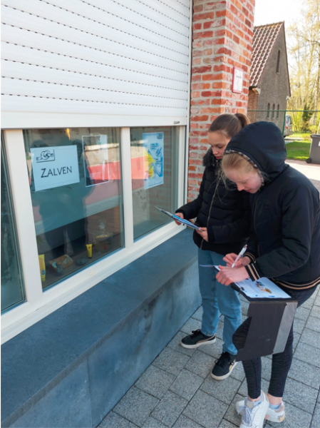 Vormelingen Julie en Liene vullen de opdracht in hun boekje in aan het raam over zalven in SGW 