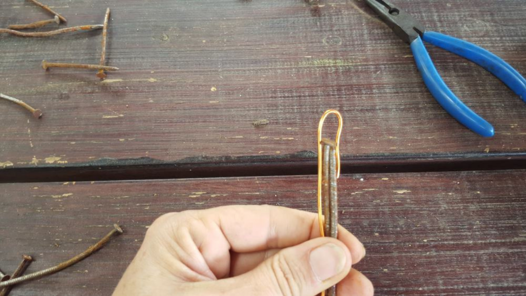 Begin met het maken van een kleine lus in de koperdraad. Plaats de lus bovenaan 2 lange nagels zoals hierboven weergegeven. 