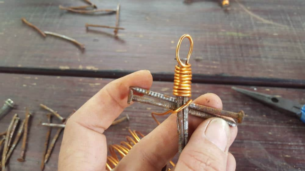 Plaats de 2 kortere nagels over de lange nagels op ongeveer 1/3 van de weg naar beneden, en steek de draad kriskras over het punt waar de nagels samenkomen. 