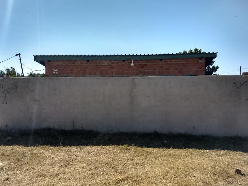 Inleefproject Zambia: grijze muur voor de schilderwerken. © Team Zambia