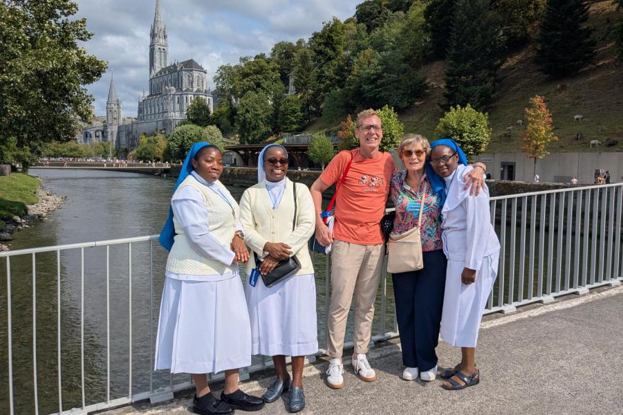 Groepsleider Guy, zijn mama en zusters in Lourdes, met de basiliek op de achtergrond © Pastorale zone Leuven aan de Dijle