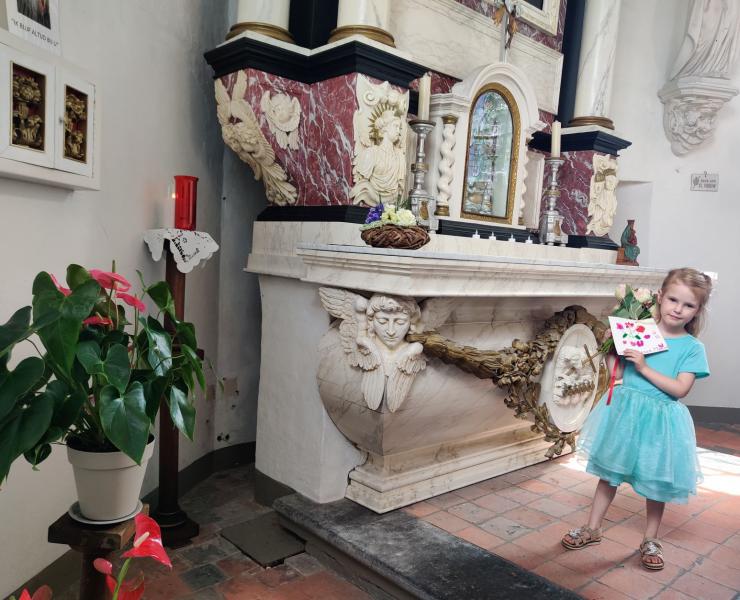 Nora brengt een bloemetje en tekening voor Maria. © parochie onze lieve Vrouw Lichtaart