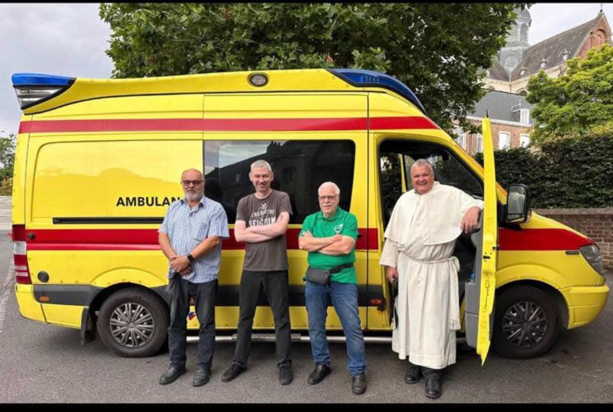 Pater Karel en enkele oud-scouts bij het vertrek van een ziekenwagen 