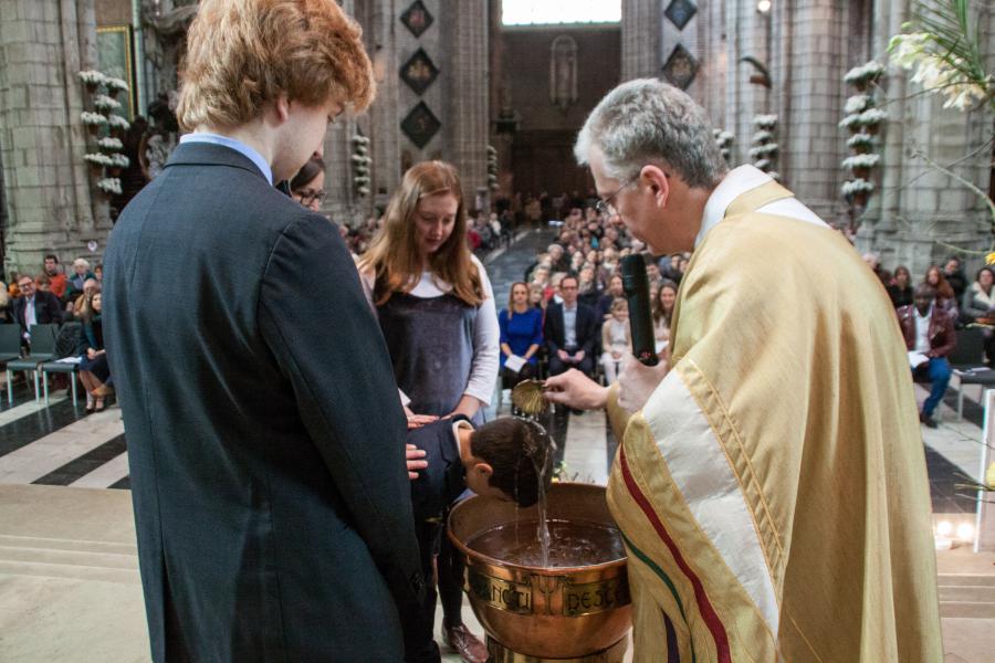 Een aandachtige kathedraal tijdens de doop van 4 jonge kinderen 