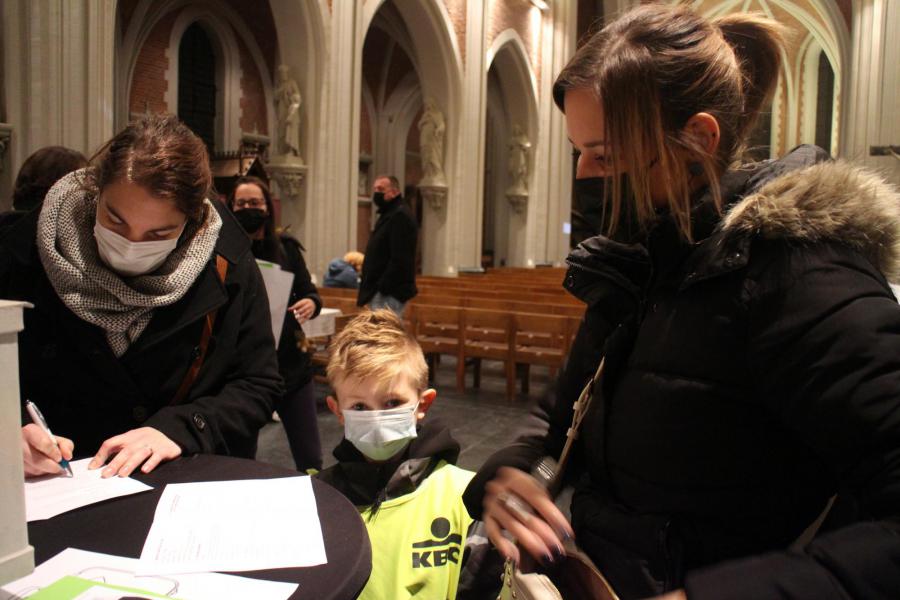 Kinderen kijken blij toe als mama/papa hen inschrijven voor hun eerste communie © RvH