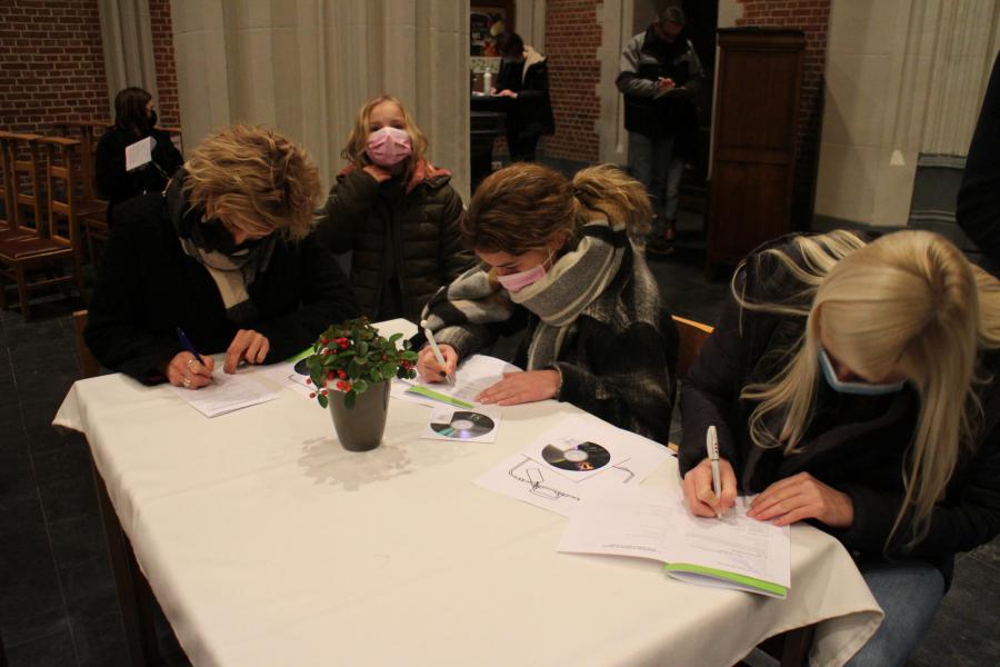 Kinderen kijken blij toe als mama/papa hen inschrijven voor hun eerste communie © RvH