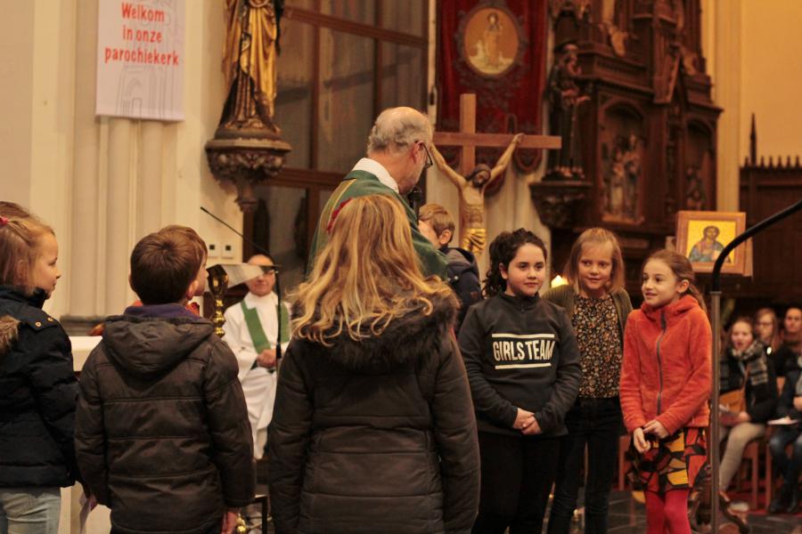 De kinderen krijgen een woordje uitleg van meneer Pastoor. © Kerk Stekene en Sint-Gillis-Waas