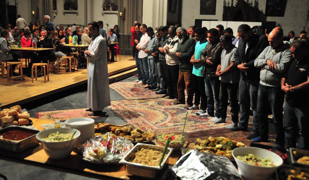 De imam gaat voor in het gebed, terwijl de gezamenlijke maaltijd al klaar staat.