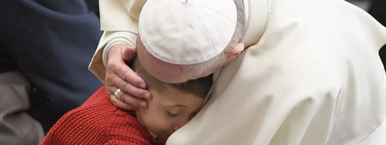 Paus Franciscus knuffelt een kind tijdens de algemene audiëntie © SIR