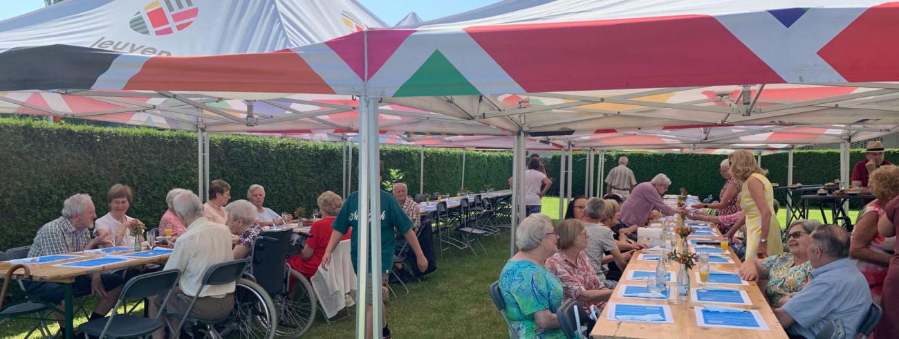 De aanwezigen genieten samen van een gezellige maaltijd in de schaduw van de pastorijtuin © Pastorale zone Leuven aan de Dijle