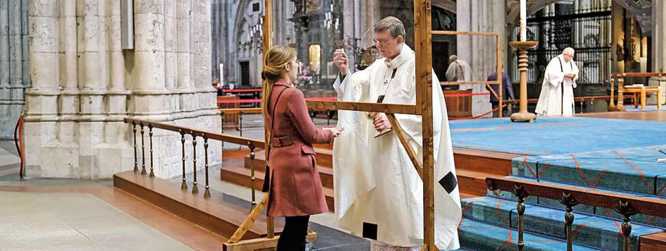 Uitreiking van de communie in de Dom van Keulen, voortaan achter plexiglas.  © KNA-Bild