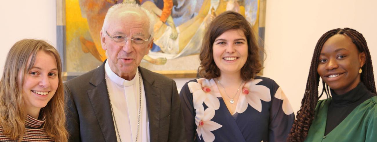 Kardinaal Jozef De Kesel omringd door – van links naar rechts – Katelijne Verhelst, Laura Vannotten en Stacey Osei.   © Geert De Kerpel
