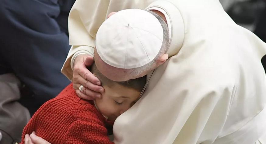 Paus Franciscus knuffelt een kind tijdens de algemene audiëntie © SIR