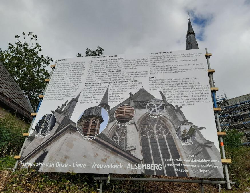 Het bord trekt onze aandacht niet alleen naar de tekst maar ook naar de kerk iets hoger gelegen 