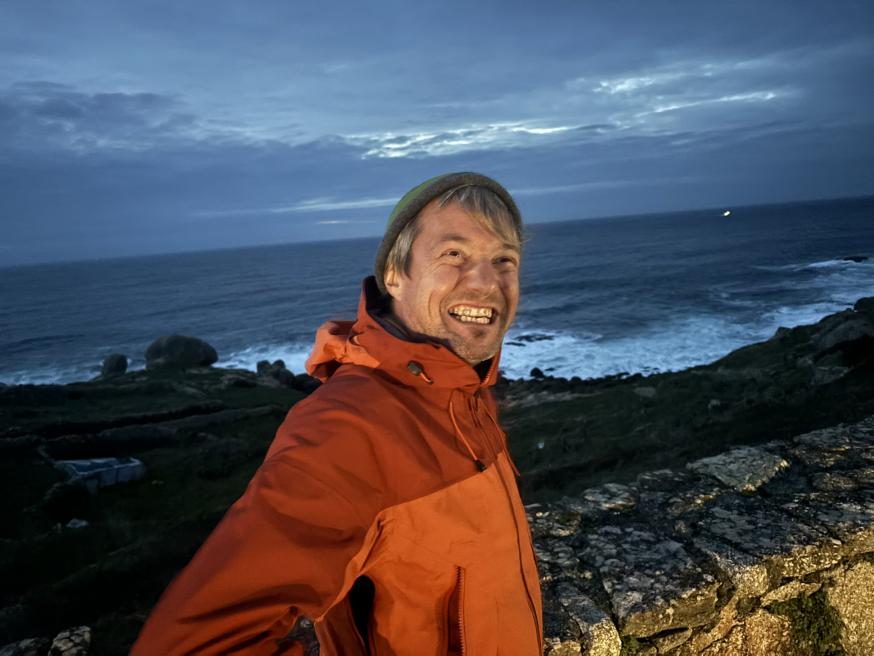 Een dolgelukkige pelgrim komt aan in Finistère, het einde van de wereld. 