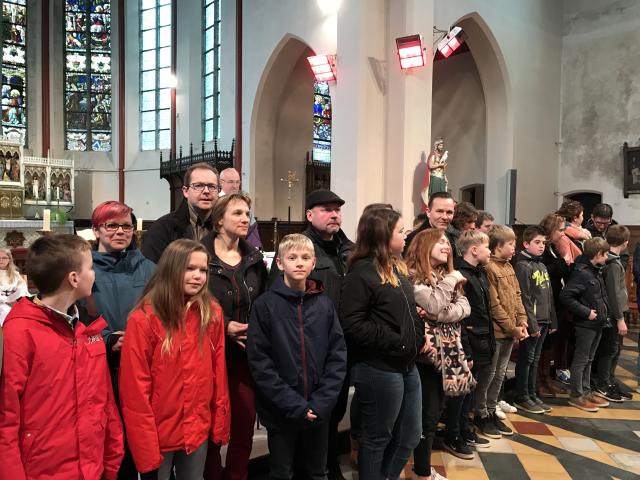 De kandidaat-vormelingen ontvangen het vormselkruisje van hun ouders. 
