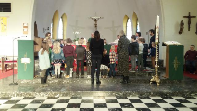 Hier zie je de aanwezige kinderen rond het altaar voor het bidden van het Onze Vader 
