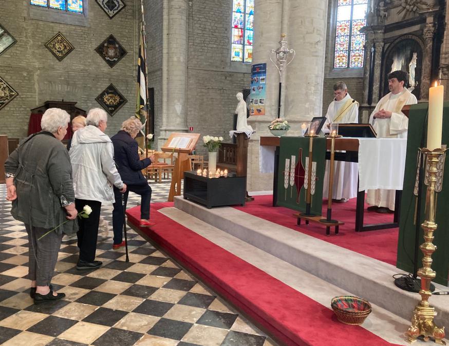 VIERING MARA-TENHEMELOPNEMING --- F4471F35.jpg met onderschrift --- Aanwezigen plaatsen een roos bij het beeld van Maria. Daar branden ook kaarsjes om haar onze dank te betuigen. Naast priester Jan staat diaken Paul Van Assche die de bedevaarten mee begel 